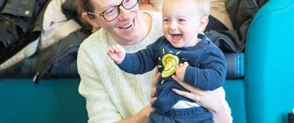 A mother holds their baby who is laughing