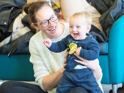 A mother holds their baby who is laughing