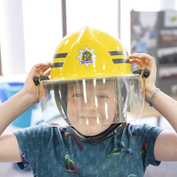 A boy wearing a large yellow fire fighter's helmet