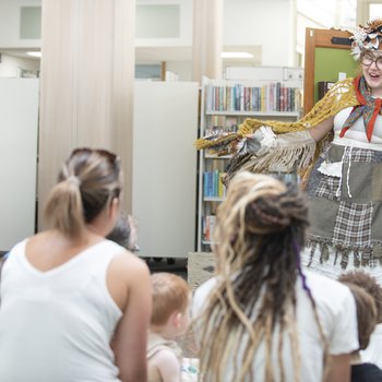 A theatre performer acting in front of a group in a library.