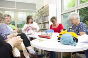 five women sat round a table knitting