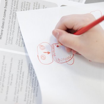 Close up of child hand drawing with red crayon