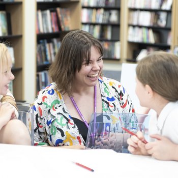 Author Alice Harman talking to two school children sat at a table