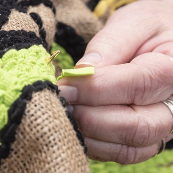Hand showing rag rug technique on a black and green striped rug