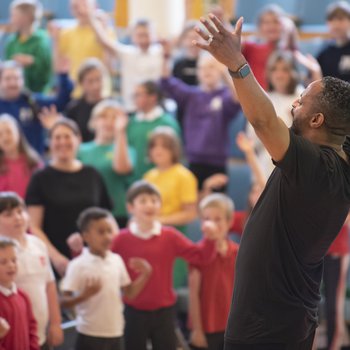 A man conducting a large group of children singing.