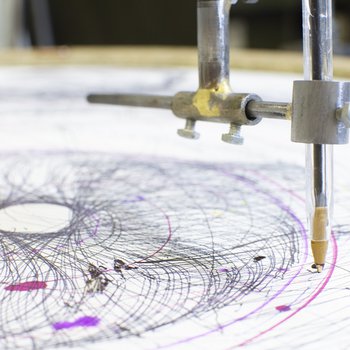 A drawing machine making circular marks on a piece of paper using a biro