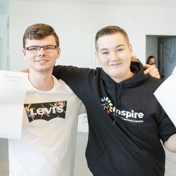 Two students holding their GCSE results proudly.