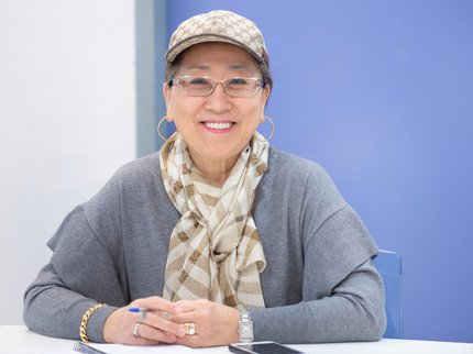 A smiling woman wearing a cap and glasses