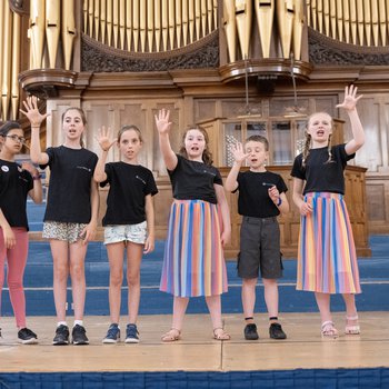 A group of children singing in the row on stage