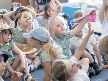 A group of school children raise their hands