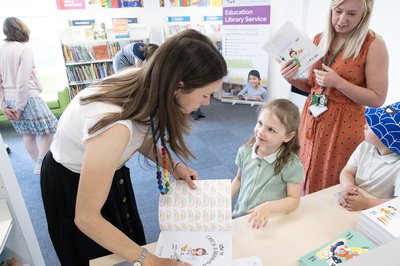 An author reads her book to a child next to a table