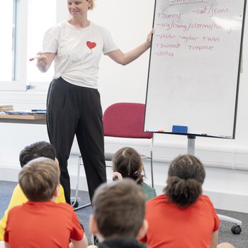Author Donna David stood next to a white board talking to school children sat on the floor