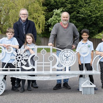 a groupf of people stand next to a metal bench