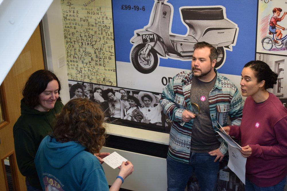 group of people looking at clues placed on table to escape from the Archives