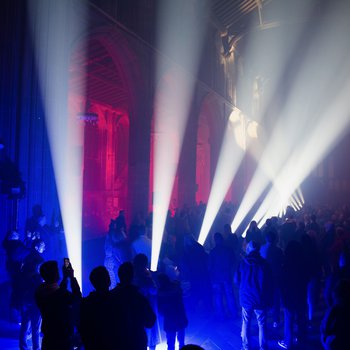 Interior of dark church with crowds of people and beams of light