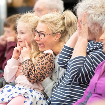 A group of adults and children watching a theatre production.