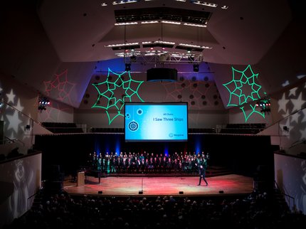 A stage of children in a choir singing
