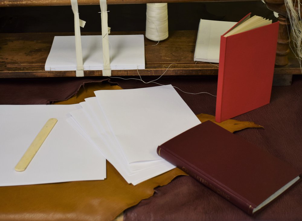 Image of sheets of paper, books and binding equipment