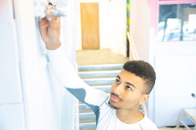 Painting and decorating male student painting a white wall
