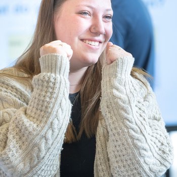 A learner looking happy with her hands up in excitement.