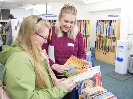 Two school teachers look at books in the ELS library