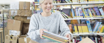 An ELS librarian unpacks a box full of books