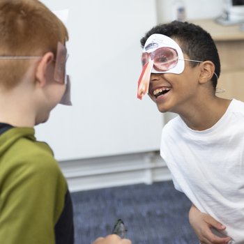 Two young children wearing masks they have made.