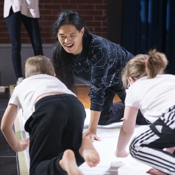 Takeshi and two children kneeled on a large sheet of paper drawing