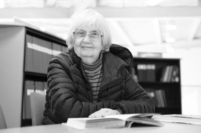 A black and white photo of an elderly woman reading.