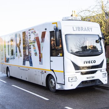 A mobile library bus driving down a road.