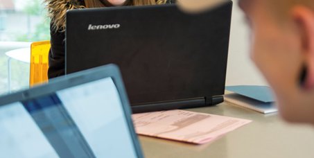 girl smiling over the top of a laptop