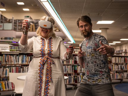 Two people wearing VR headsets in a library