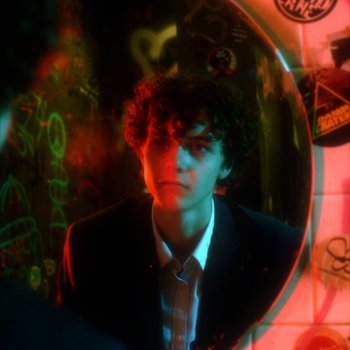 A boy with curly hair looking into a mirror surrounded by graffiti.