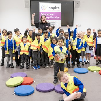 A group of children stand with an author in a library