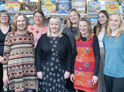 A group of women standing in front of book shelves at the ELS offices