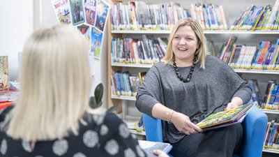 four people stand at the front of a presentation holding books