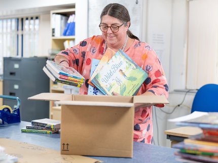 A woman putting books in boxes