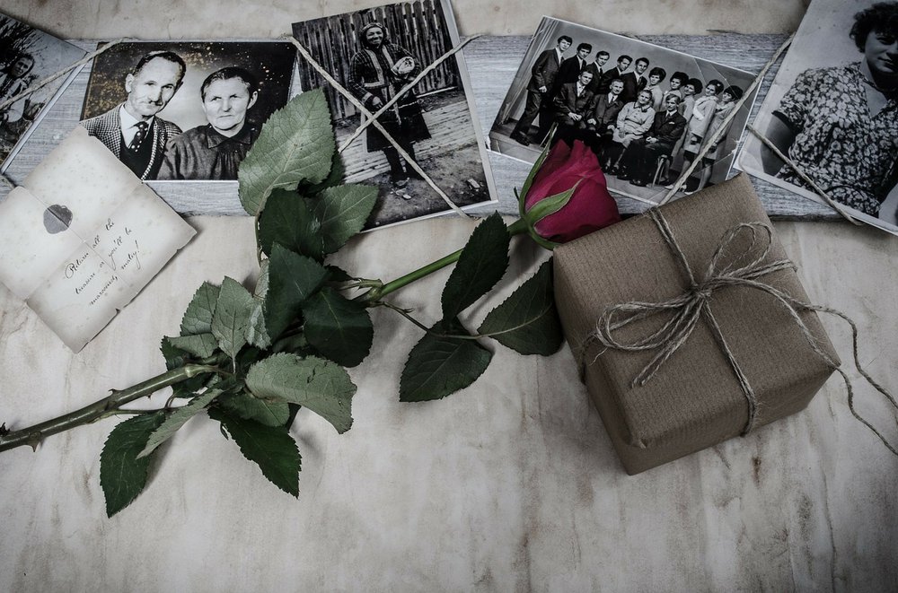 selection of black and white photographs, brown paper box and red rose