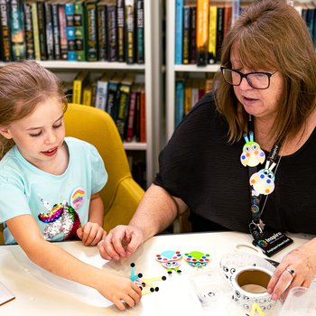 girl taking part in craft activity with adult helper