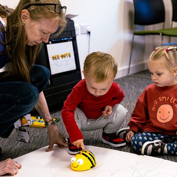young children playing with BeeBot with adult helper