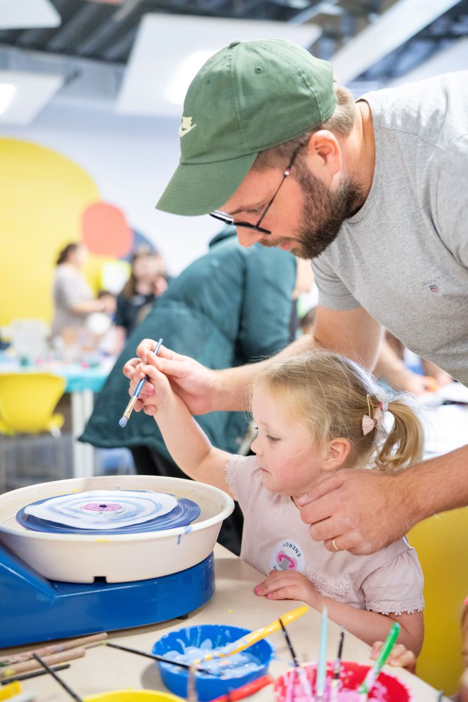little girl and dad using a paint spinning wheel