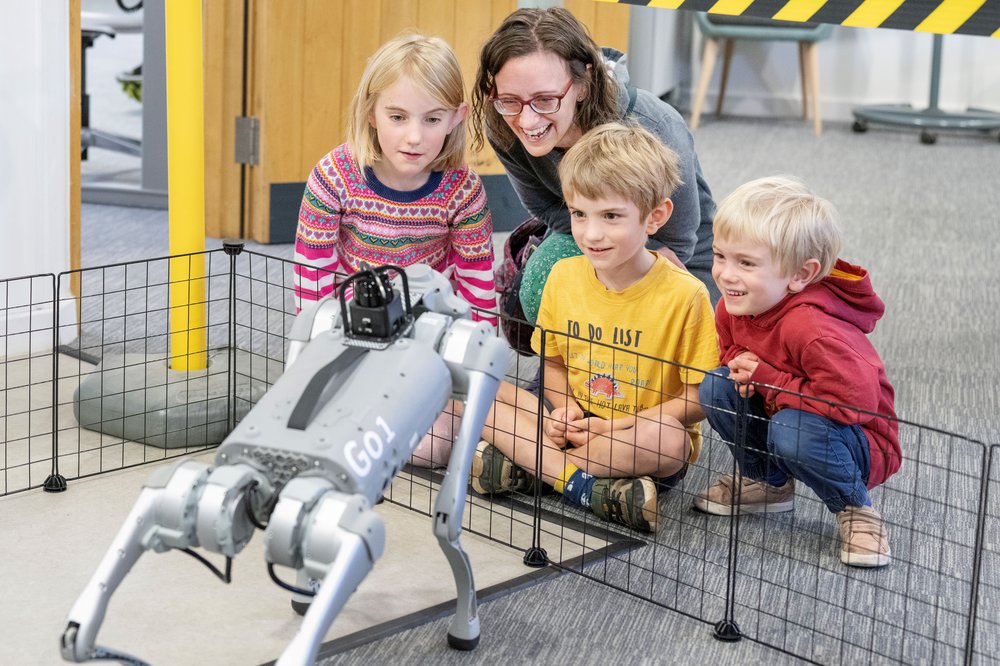 Mum and 3 children looking at robot dog
