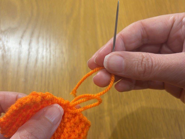 Tying a knot in a yarn tail on the side of a piece of knitting