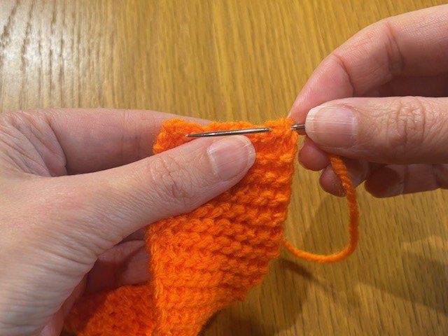 Sewing a yarn tail into the end of a piece of knitting