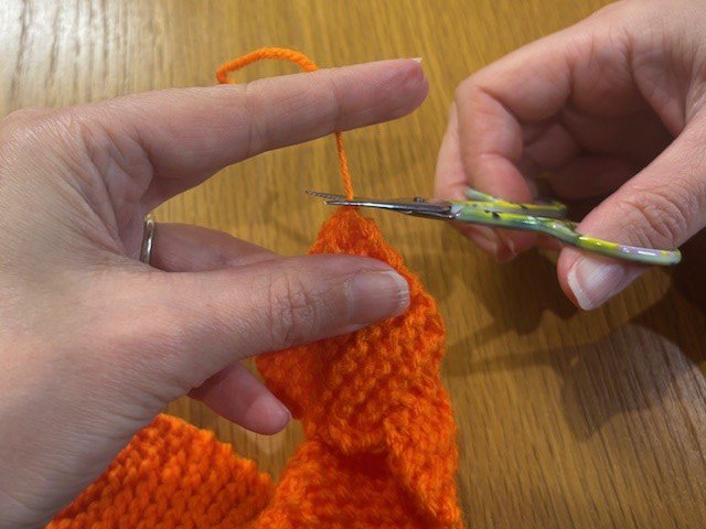 Snipping the yarn tail off a knitting project