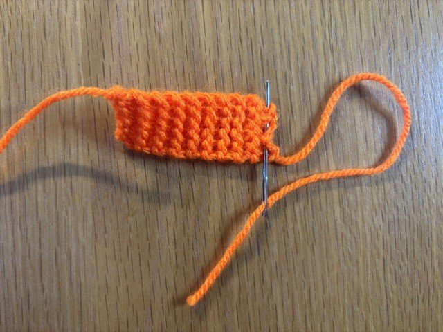 Running a line of stitches along the end of a knitting project with the yarn tail