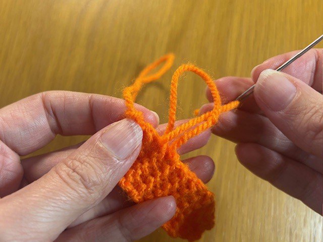 Stitching a yarn tail along the side of a project, then knotting the last stitch to secure it