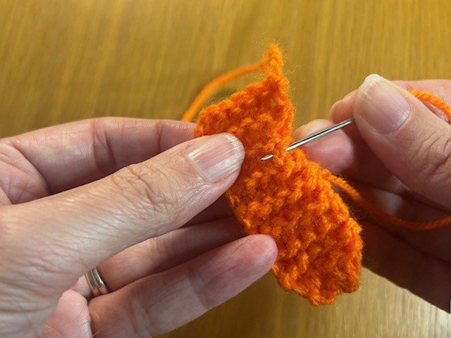 Running a line of stitches across the back of a knitting project with the yarn tail