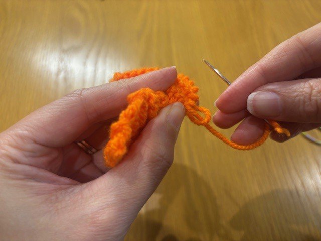 Tying a knot in a yarn tail to secure a gathered section of the project