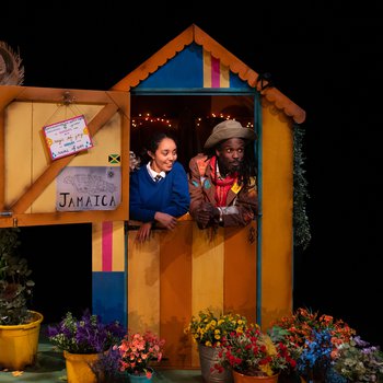 Schoolgirl Abi (Jazmine Wilkinson) and Grandad (Marcus Hercules) lean on the Dutch door of a brightly coloured shed surrounded by potted plants.